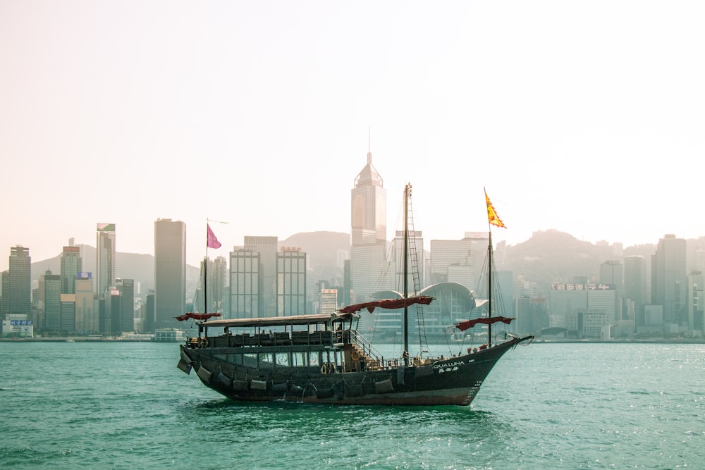 brown boat on body of water near city buildings during daytime