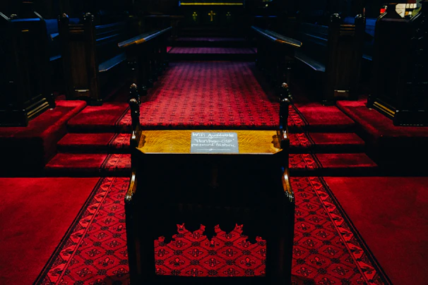 A somber scene showing a dimly lit church interior with empty pews, evoking reflection and solemnity.