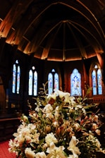A softly lit church altar decorated with pastel flowers for a wedding ceremony.
