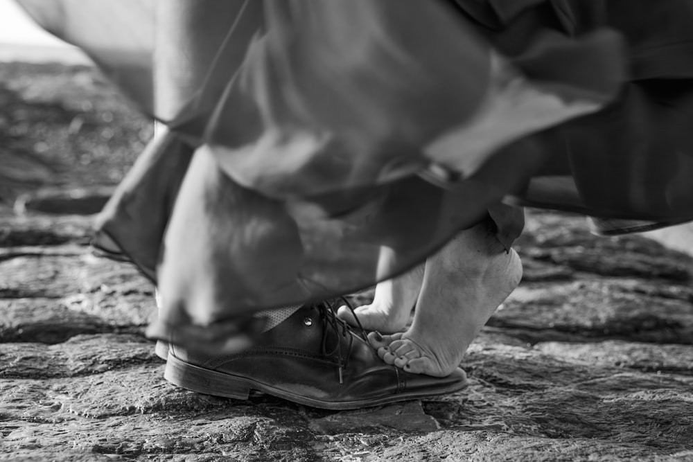 grayscale photo of person wearing black leather shoes