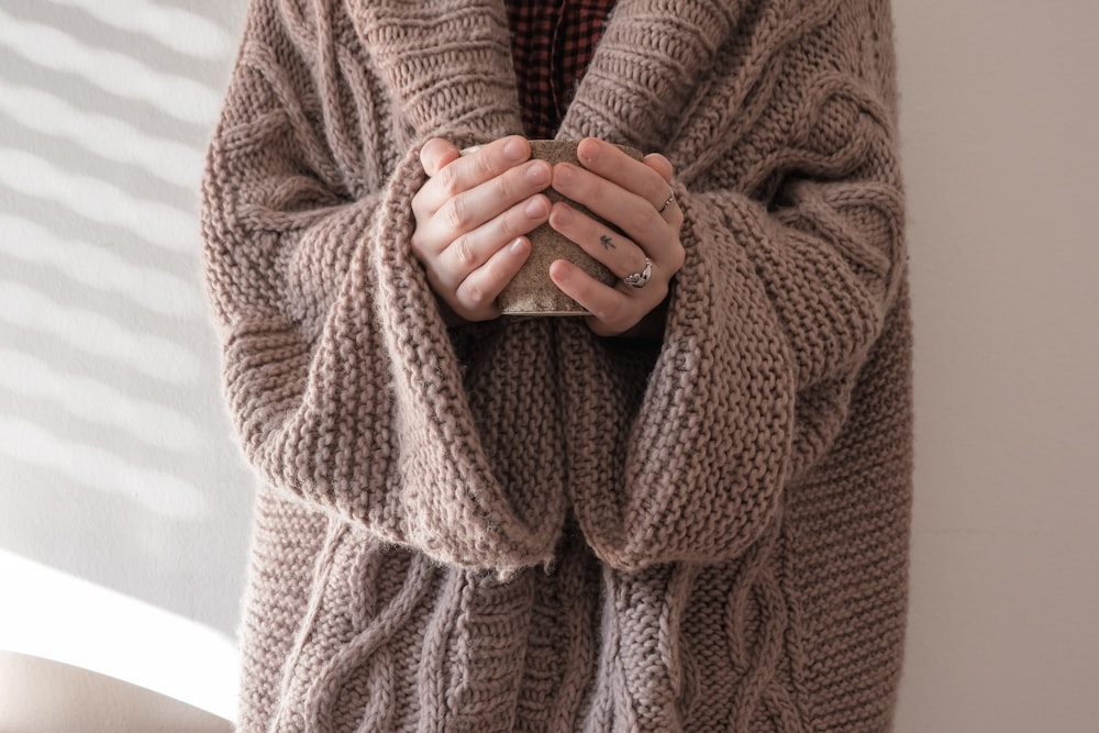 personne en pull en tricot marron