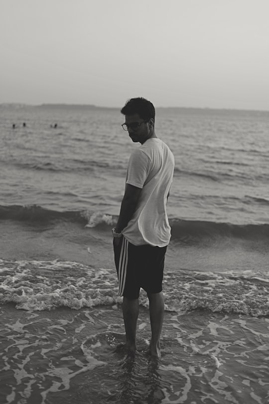 man in white shirt and black shorts standing on beach during daytime in Goa India