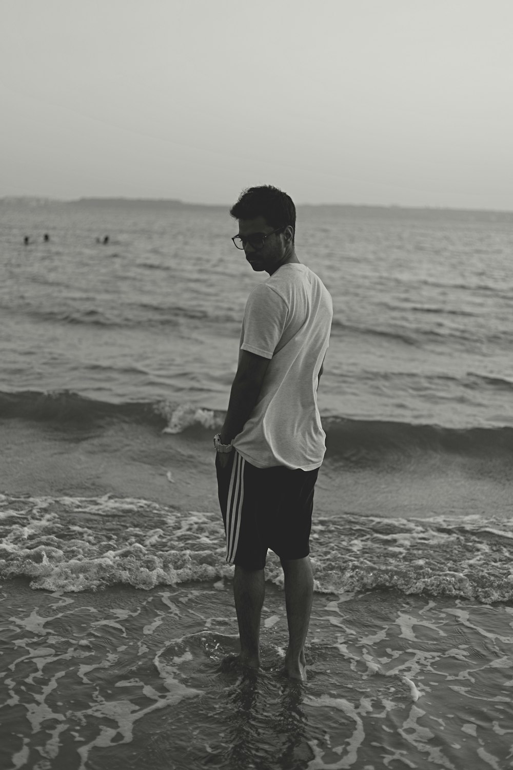 man in white shirt and black shorts standing on beach during daytime