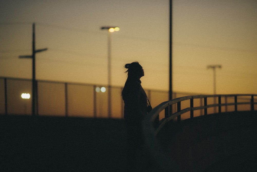 silhouette of person standing on balcony during sunset