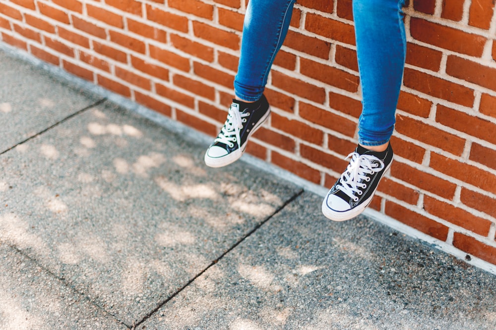 person in blue denim jeans and black and white sneakers