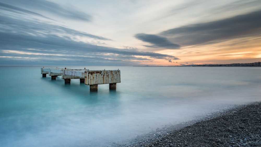 brown wooden dock on sea under cloudy sky during daytime