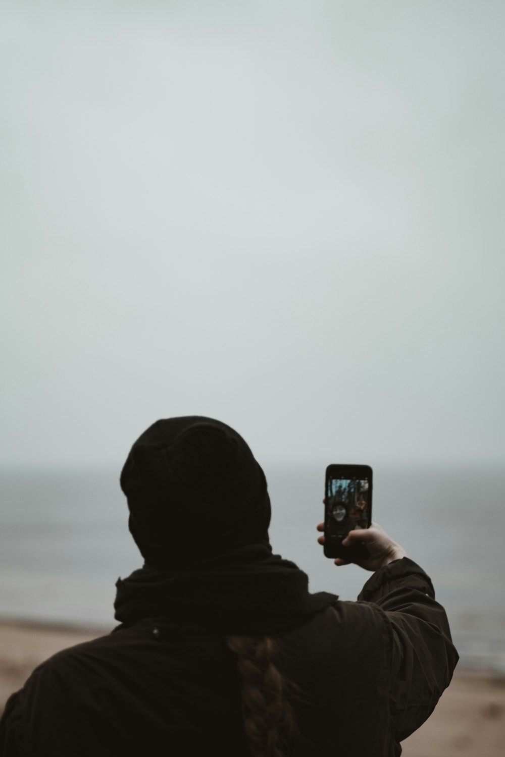 person in black hoodie holding black smartphone