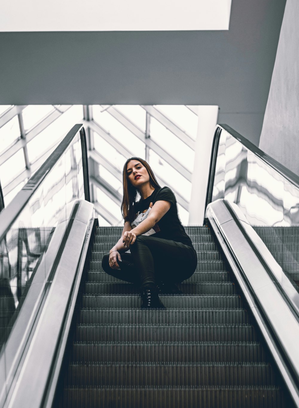 woman in black tank top and black pants sitting on black escalator