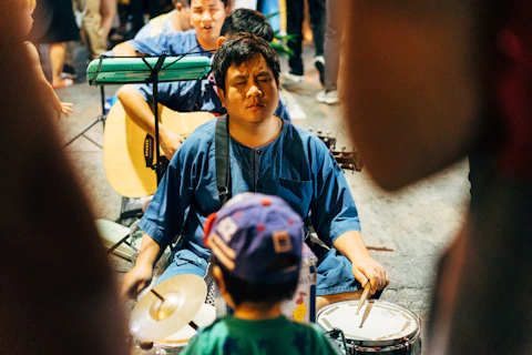 boy in blue and green crew neck shirt playing drum