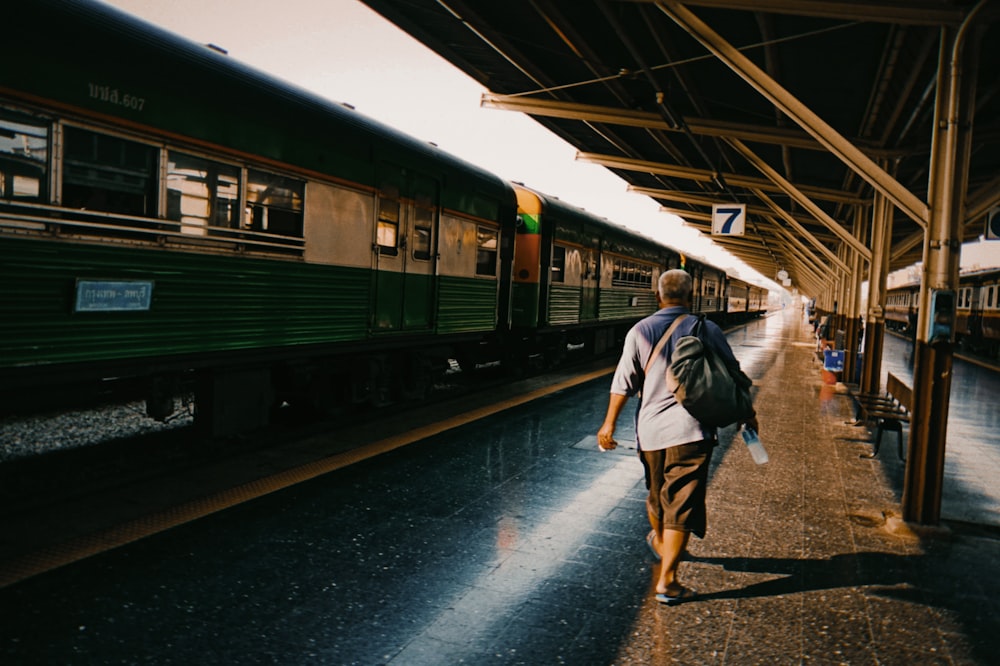 man in white shirt and brown shorts walking on train station