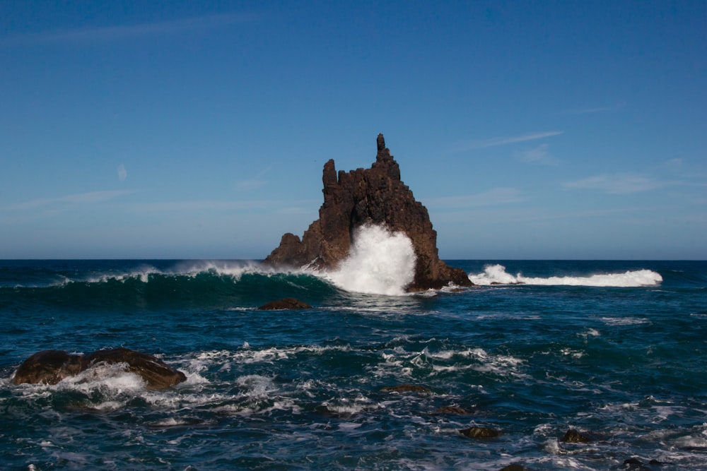 brown rock formation on sea under blue sky during daytime