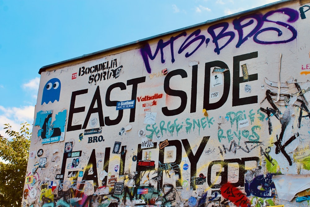 people standing near white and purple wall with graffiti during daytime