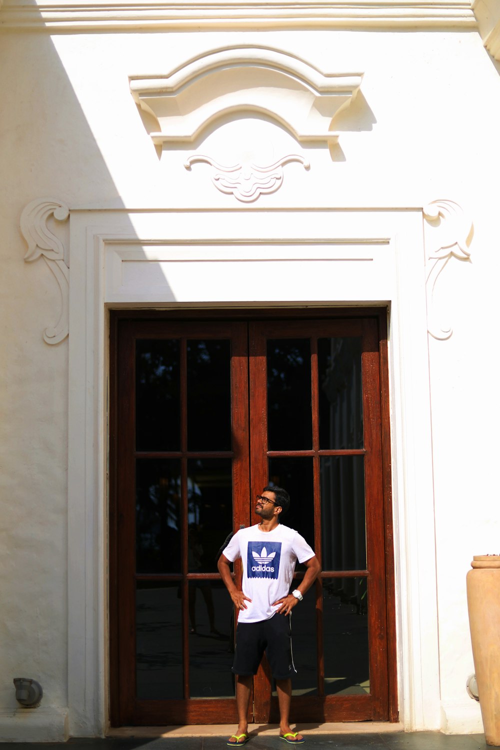man in blue and white crew neck t-shirt standing beside brown wooden door