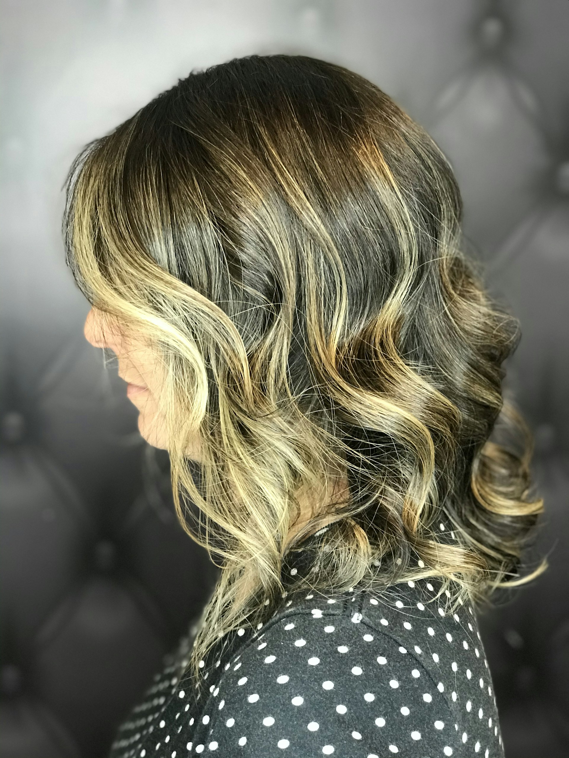 Elegant side profile of a client showcasing sleek, shiny black hair extensions with rich volume and depth.