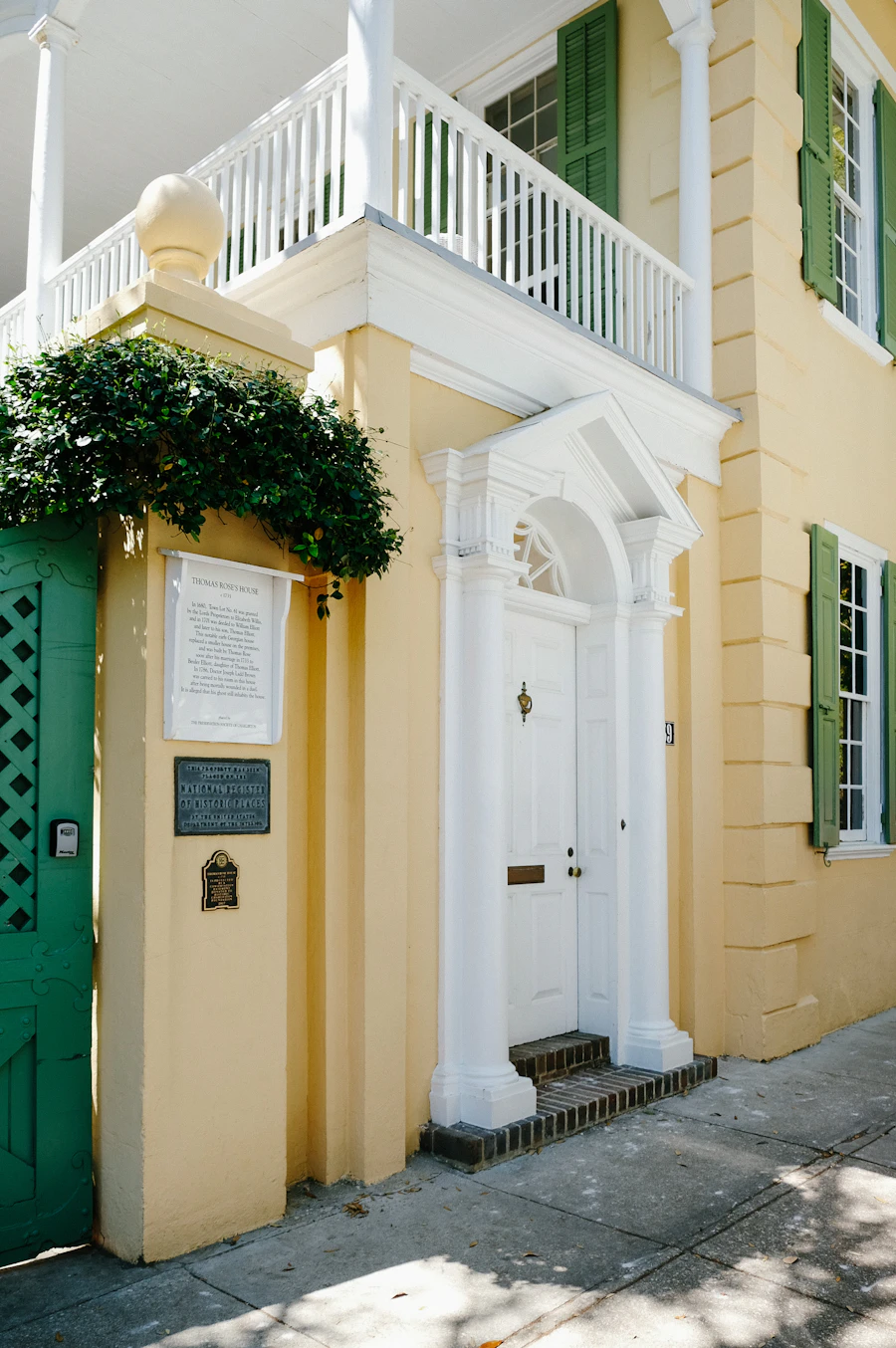 A yellow Charleston house with a white entry and balcony