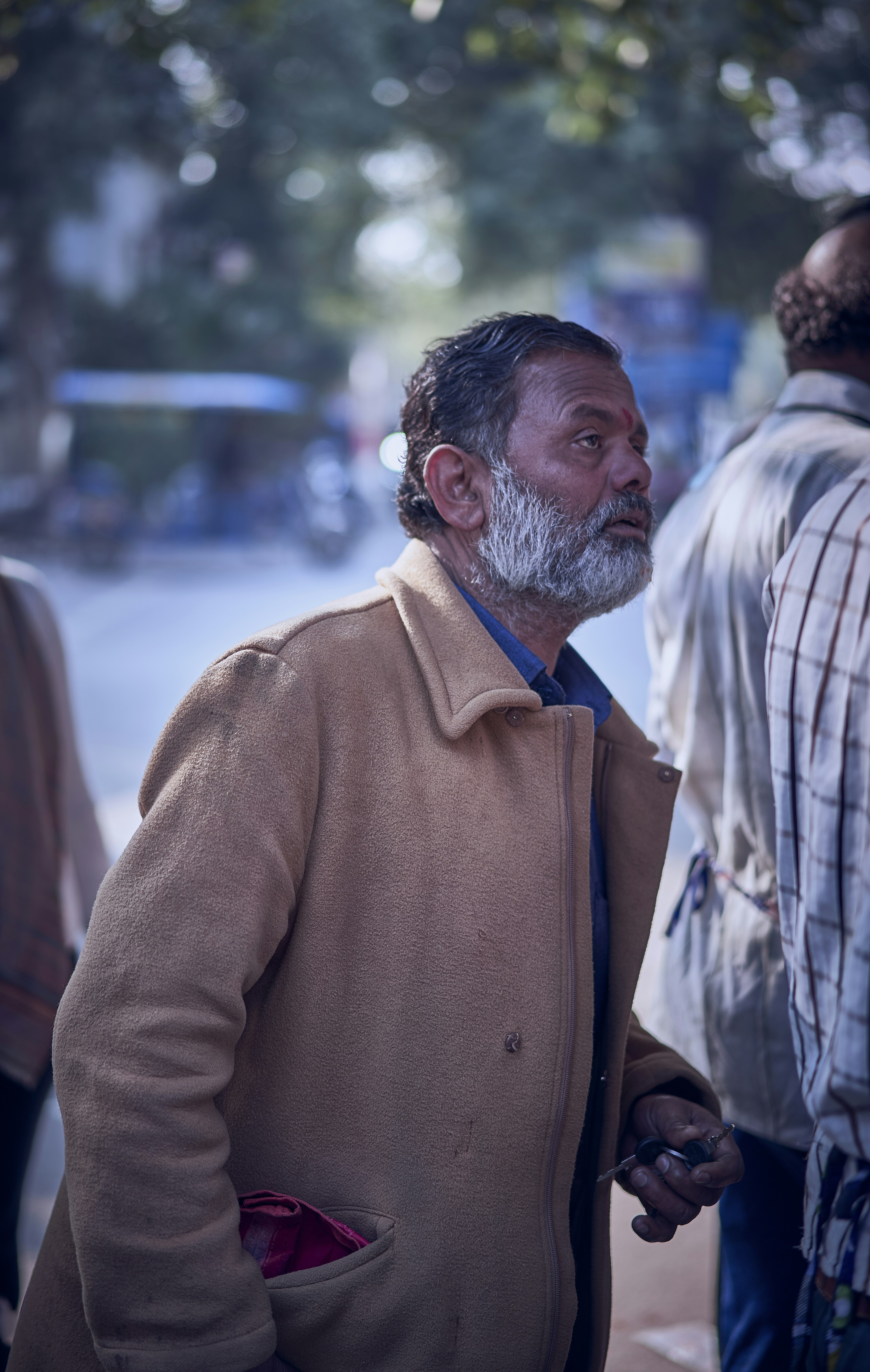 man in brown coat standing near people during daytime