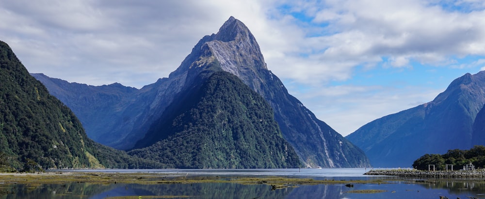 a lake surrounded by mountains under a cloudy blue sky