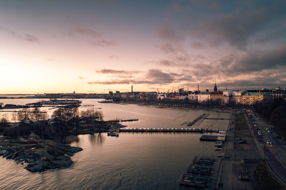 body of water near city buildings during sunset