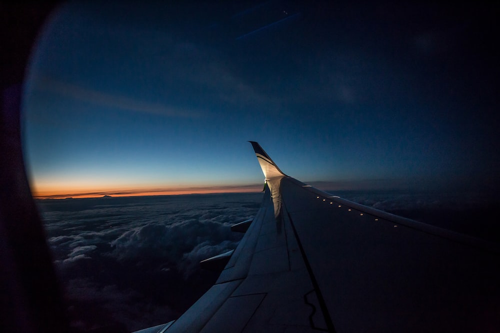 airplane wing over the clouds during sunset