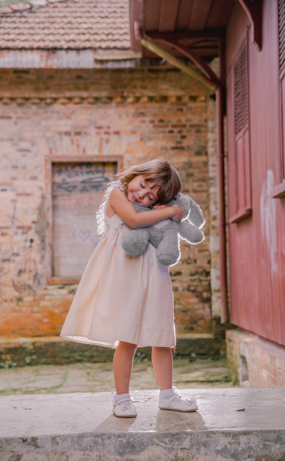 Muchacha con vestido blanco de pie junto a la puerta de madera roja durante el día