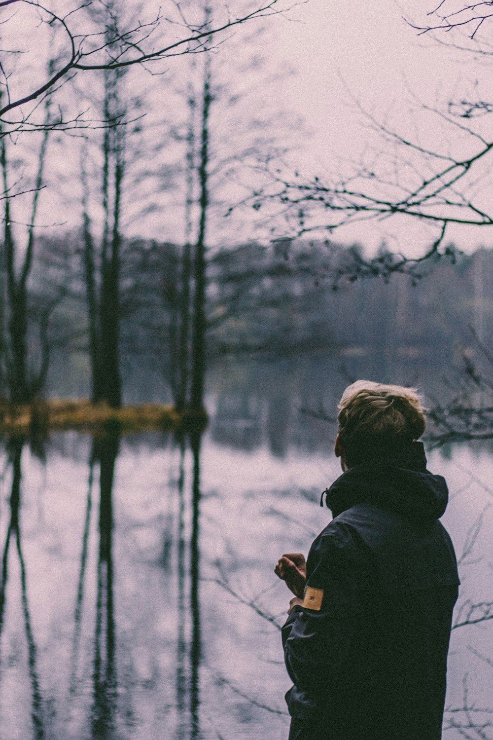 person in black jacket standing near bare trees during daytime