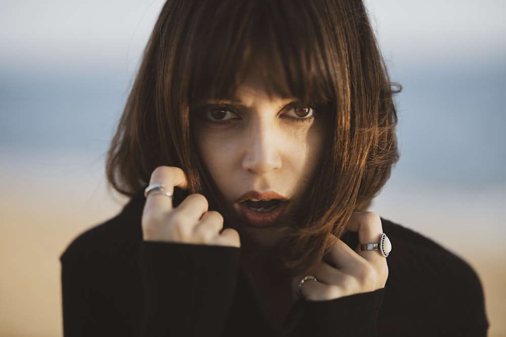 woman in black long sleeve shirt holding her chin