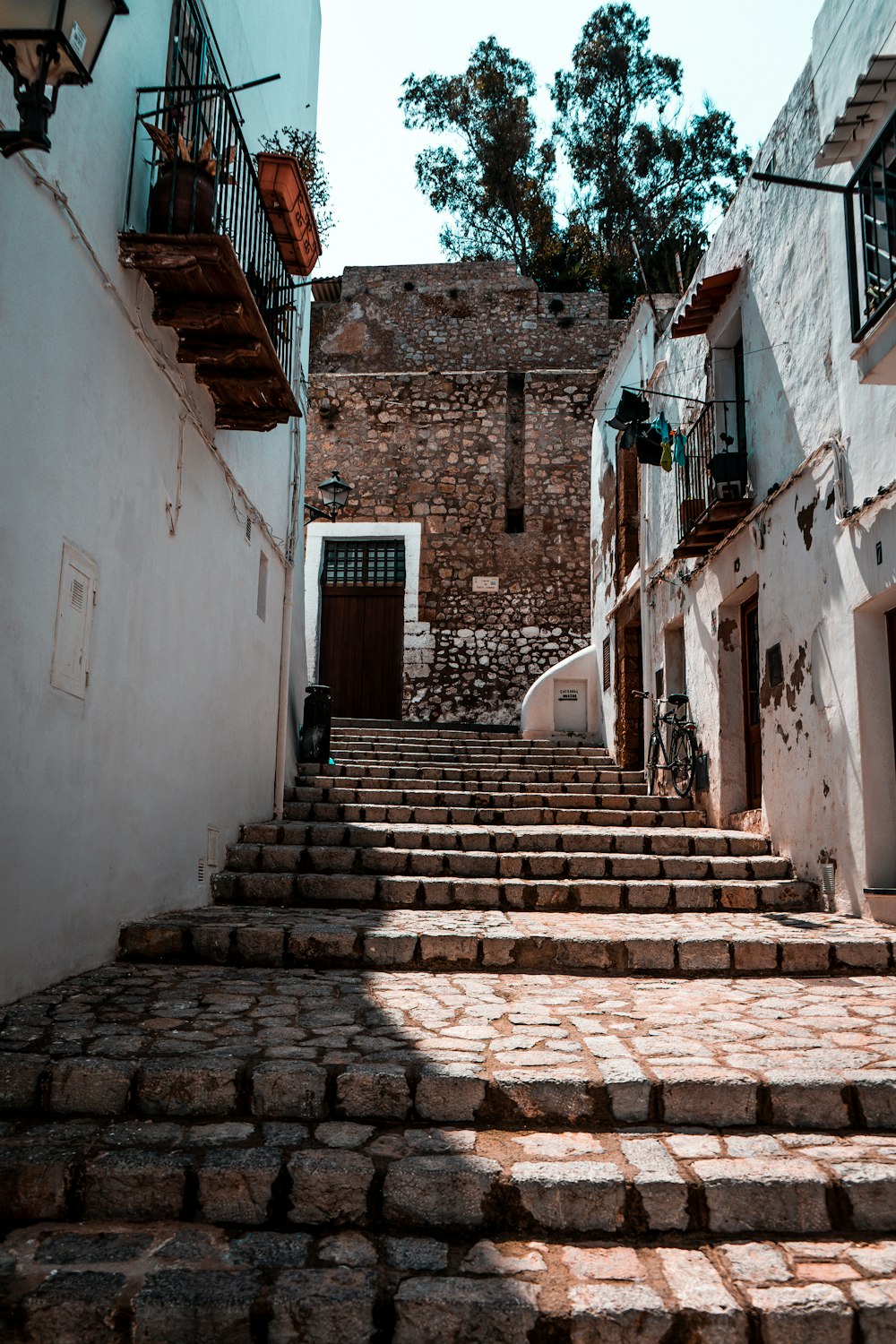 brown brick stairs between white concrete houses during daytime