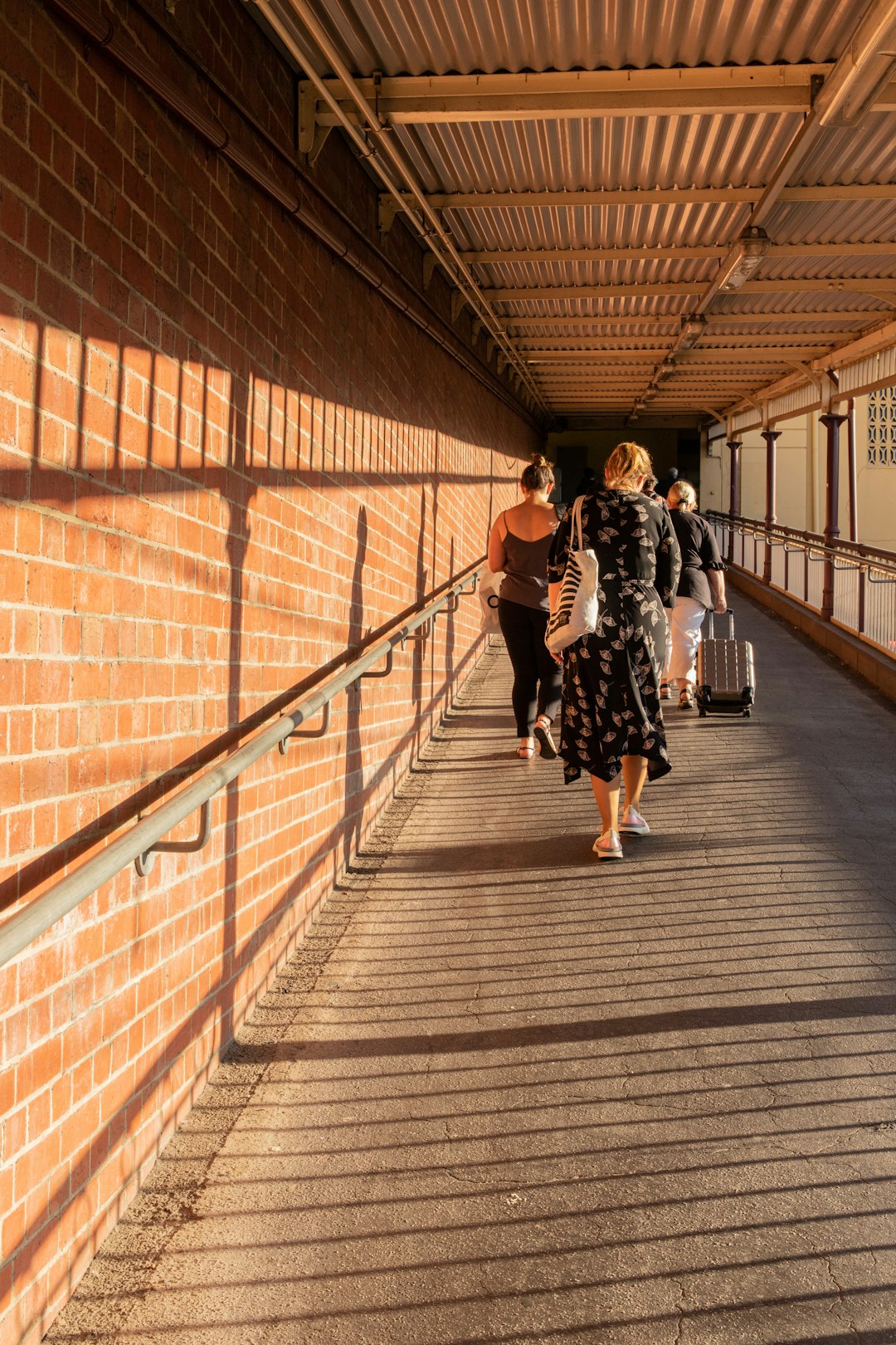 woman in black and white dress walking on brown wooden bridge