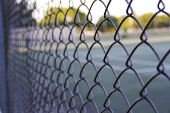grey metal fence with yellow and green string lights