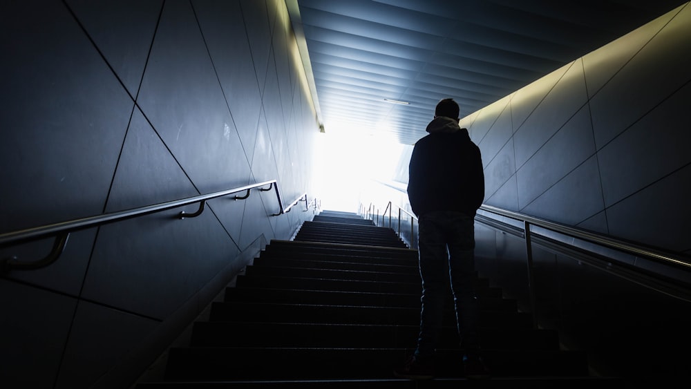 Hombre en chaqueta negra caminando por las escaleras