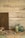 A rustic setting features a wooden sign with the words 'fresh eggs' alongside a collection of jars. One jar is filled with colorful candy-coated chocolates, while other jars are empty and have a vintage look. Brown and blue eggs are arranged on a fabric with blue stripes. The background consists of aged whitewashed wooden planks and sheer fabric drapes down softly.
