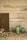 A rustic setting features a wooden sign with the words 'fresh eggs' alongside a collection of jars. One jar is filled with colorful candy-coated chocolates, while other jars are empty and have a vintage look. Brown and blue eggs are arranged on a fabric with blue stripes. The background consists of aged whitewashed wooden planks and sheer fabric drapes down softly.
