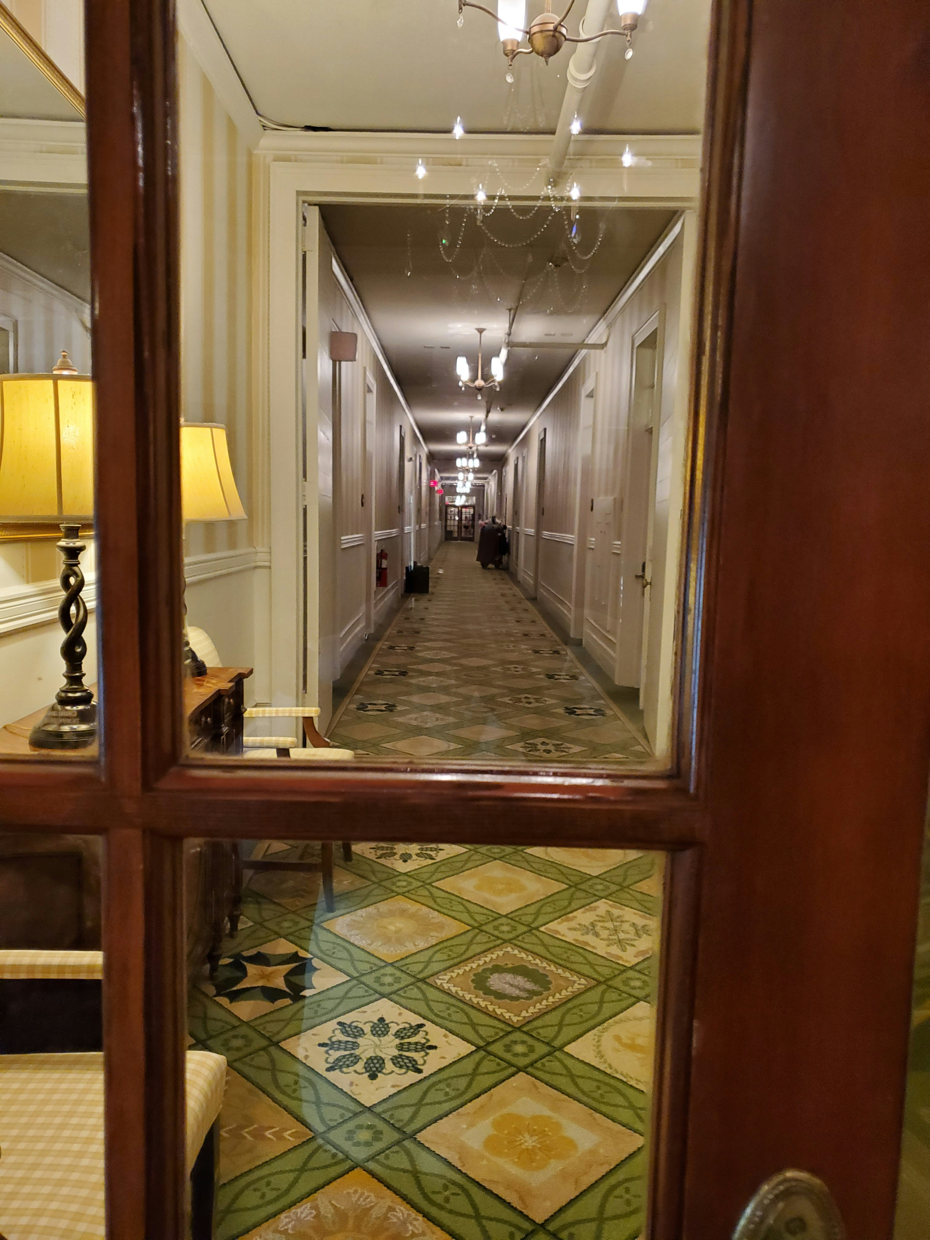 Full-length arched mirror in hotel corridor with warm lighting