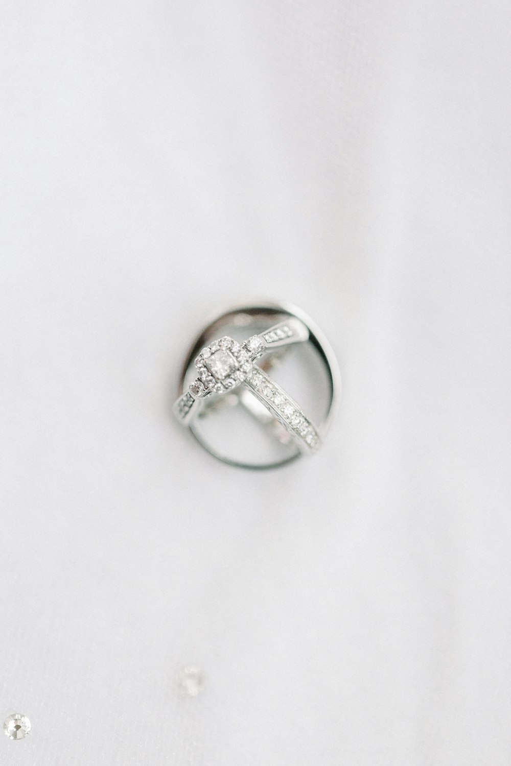 silver diamond ring on white textile