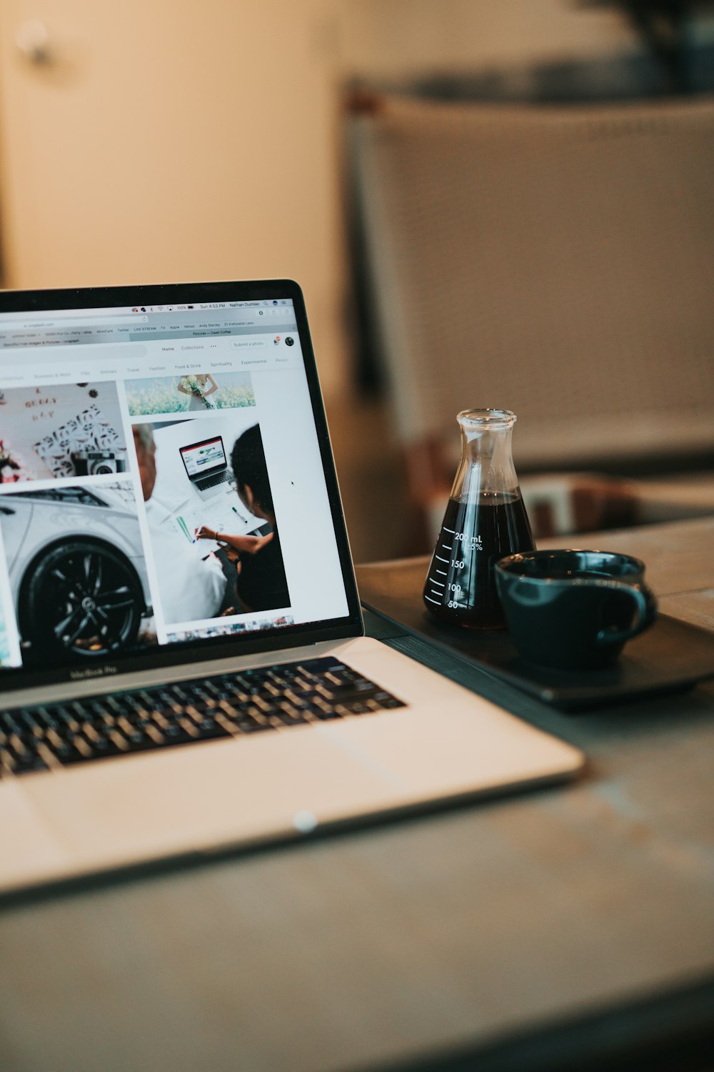 macbook air beside black ceramic mug on brown wooden table