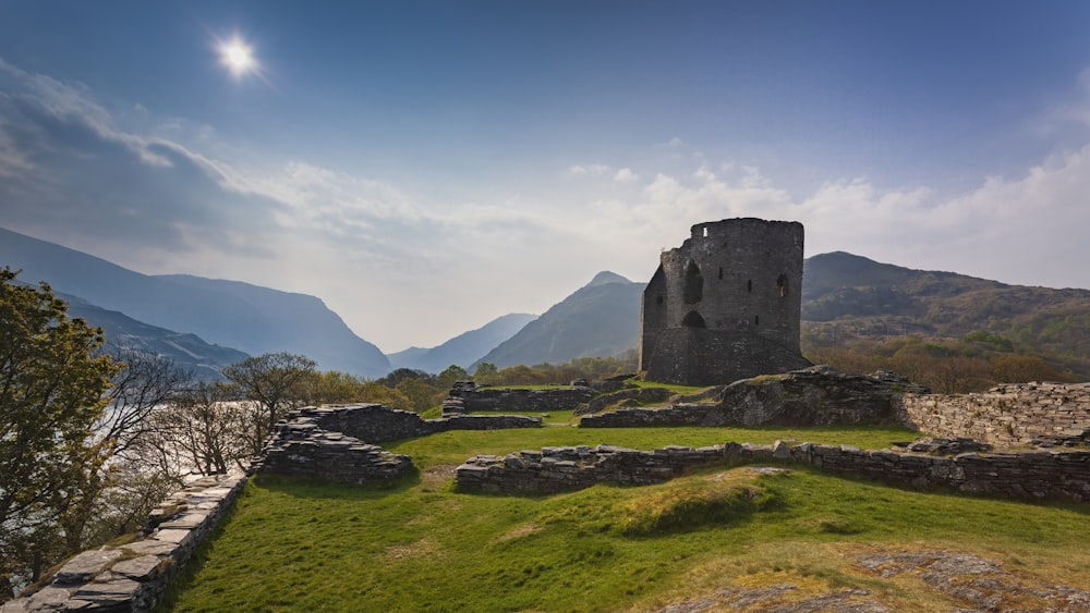 gray concrete building on green grass field near mountains under blue sky during daytime