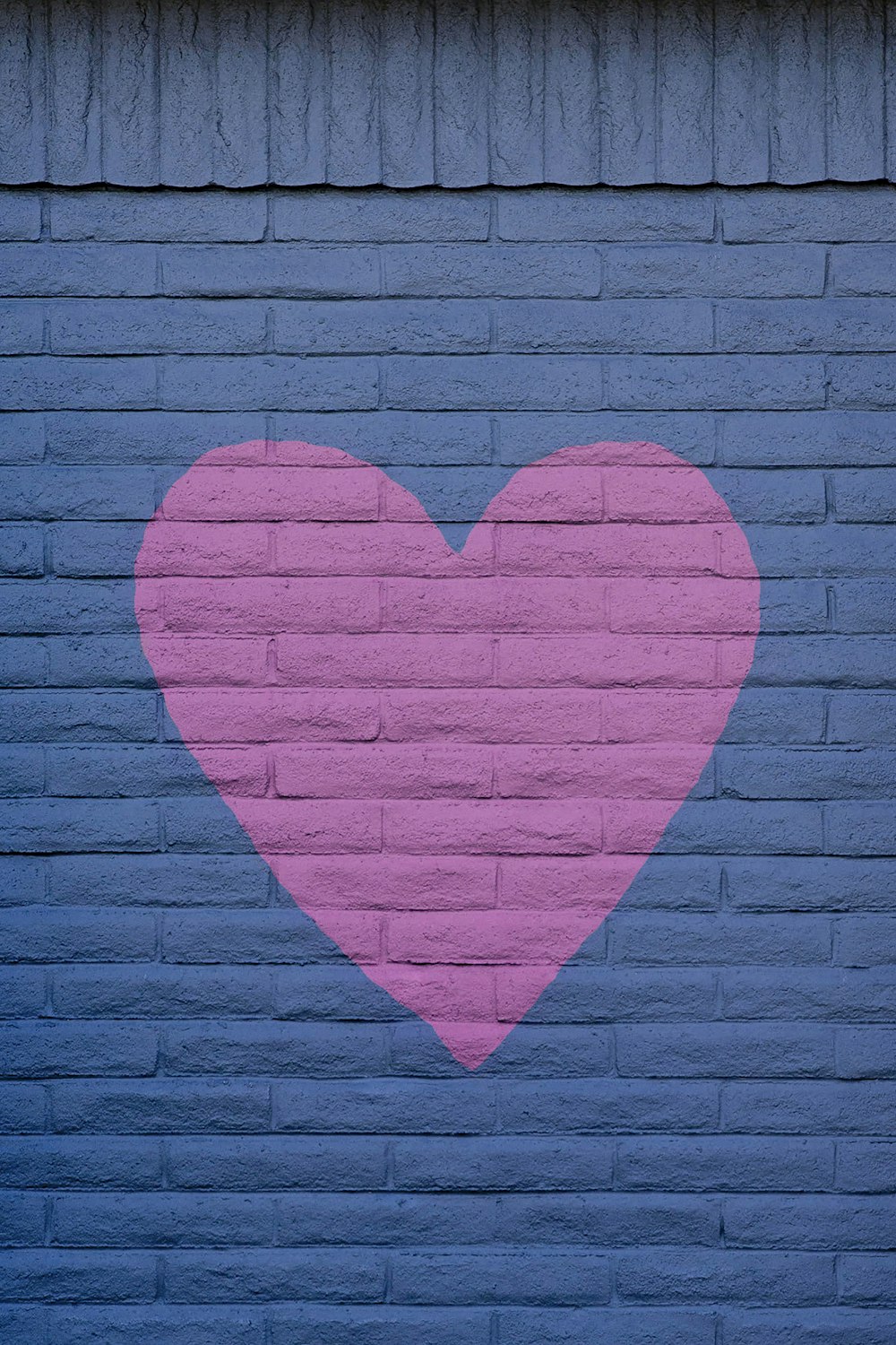 pink heart wall art on black brick wall