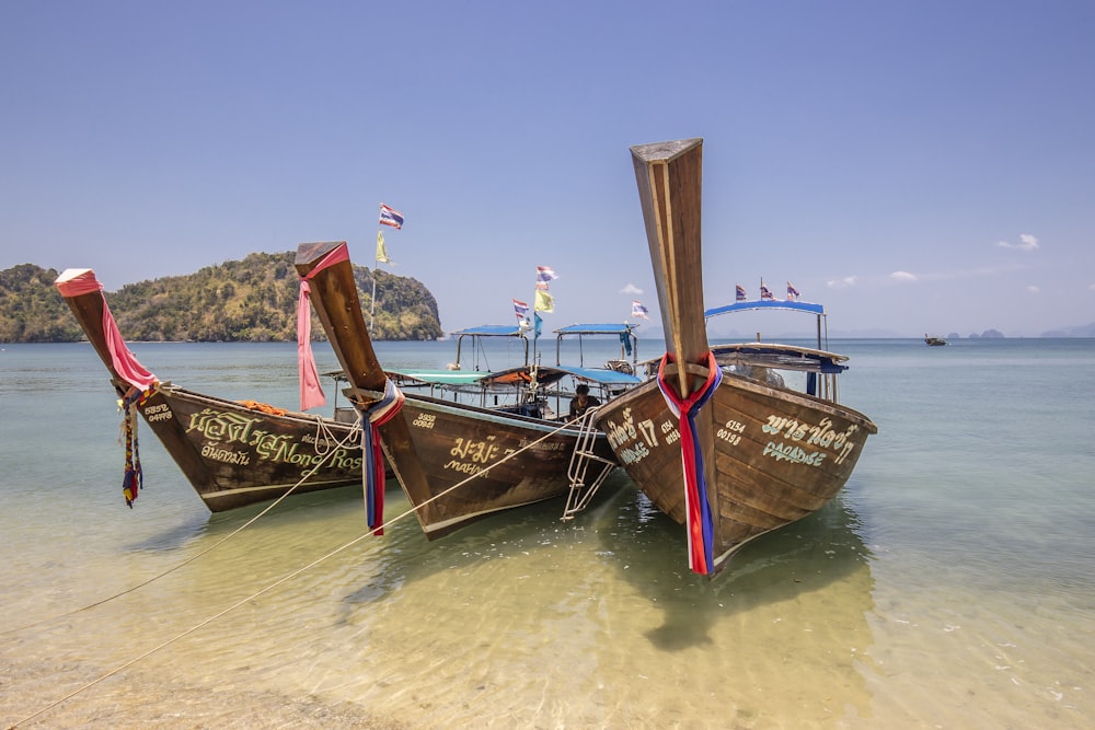 brown wooden boat on sea shore during daytime