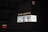A large, illuminated advertisement for Louis Vuitton is displayed on the side of a dark building. The ad features three models showcasing handbags, dressed in stylish clothing. The Louis Vuitton logo is prominently featured, along with text in both English and another language.