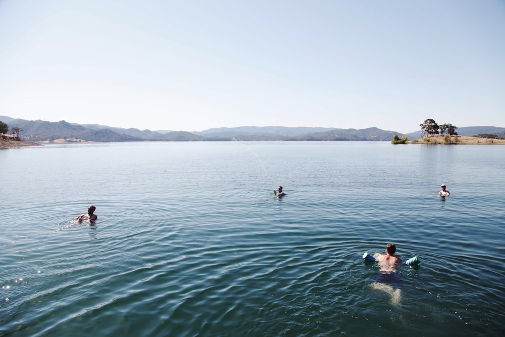 people swimming on sea during daytime