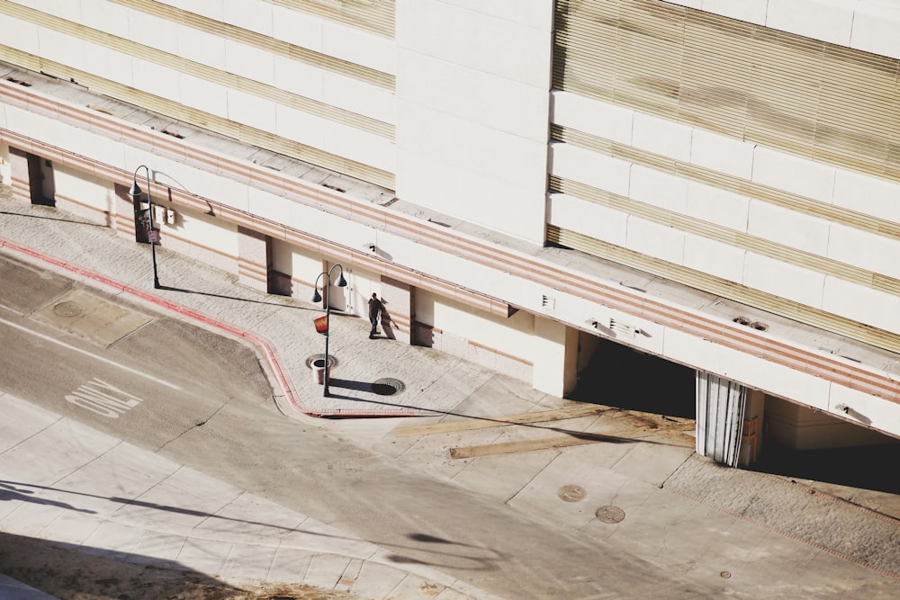 people walking on sidewalk near white concrete building during daytime