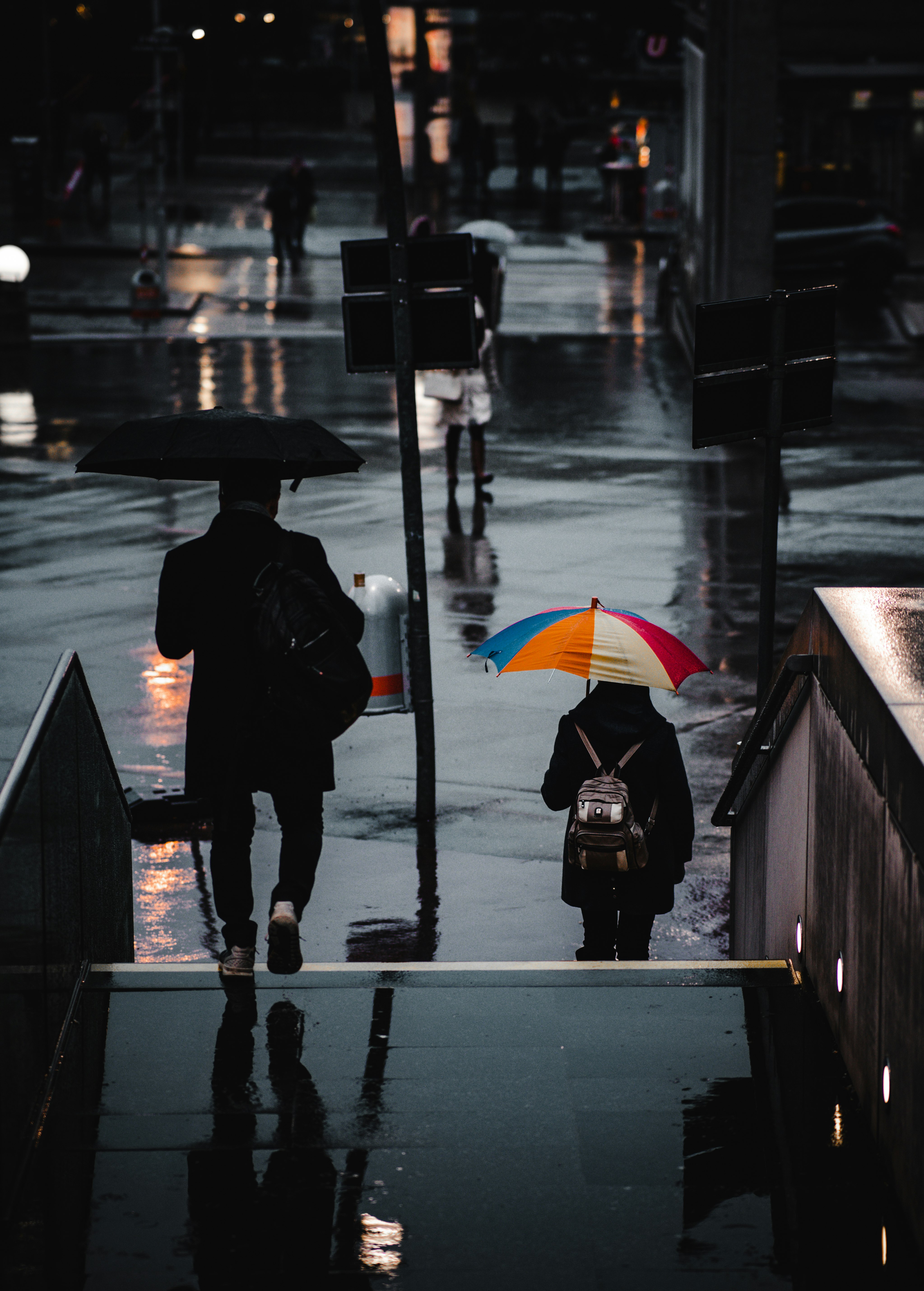 person in black coat holding umbrella standing on sidewalk during night time