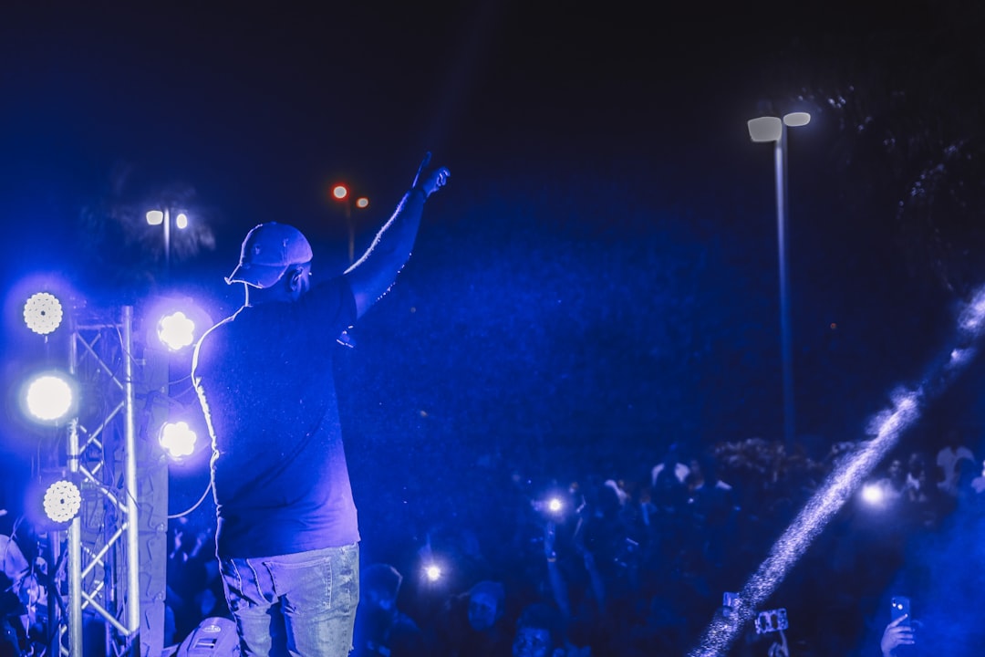 man in black t-shirt and blue denim jeans standing on stage