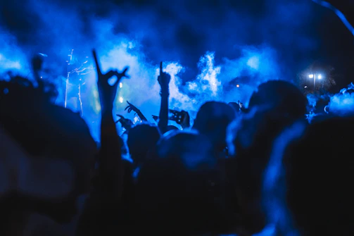 A vibrant photo of a lively crowd at a night event with glowing blue and black lights.