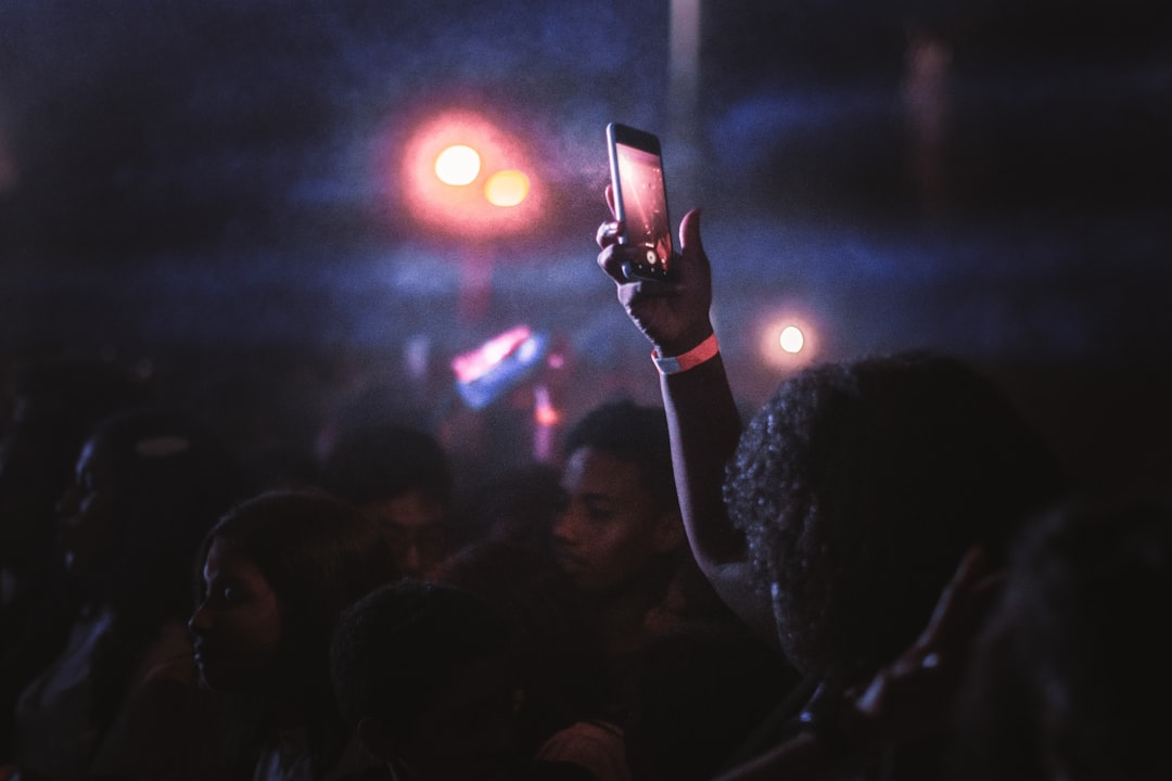 person holding black smartphone taking photo of crowd during night time