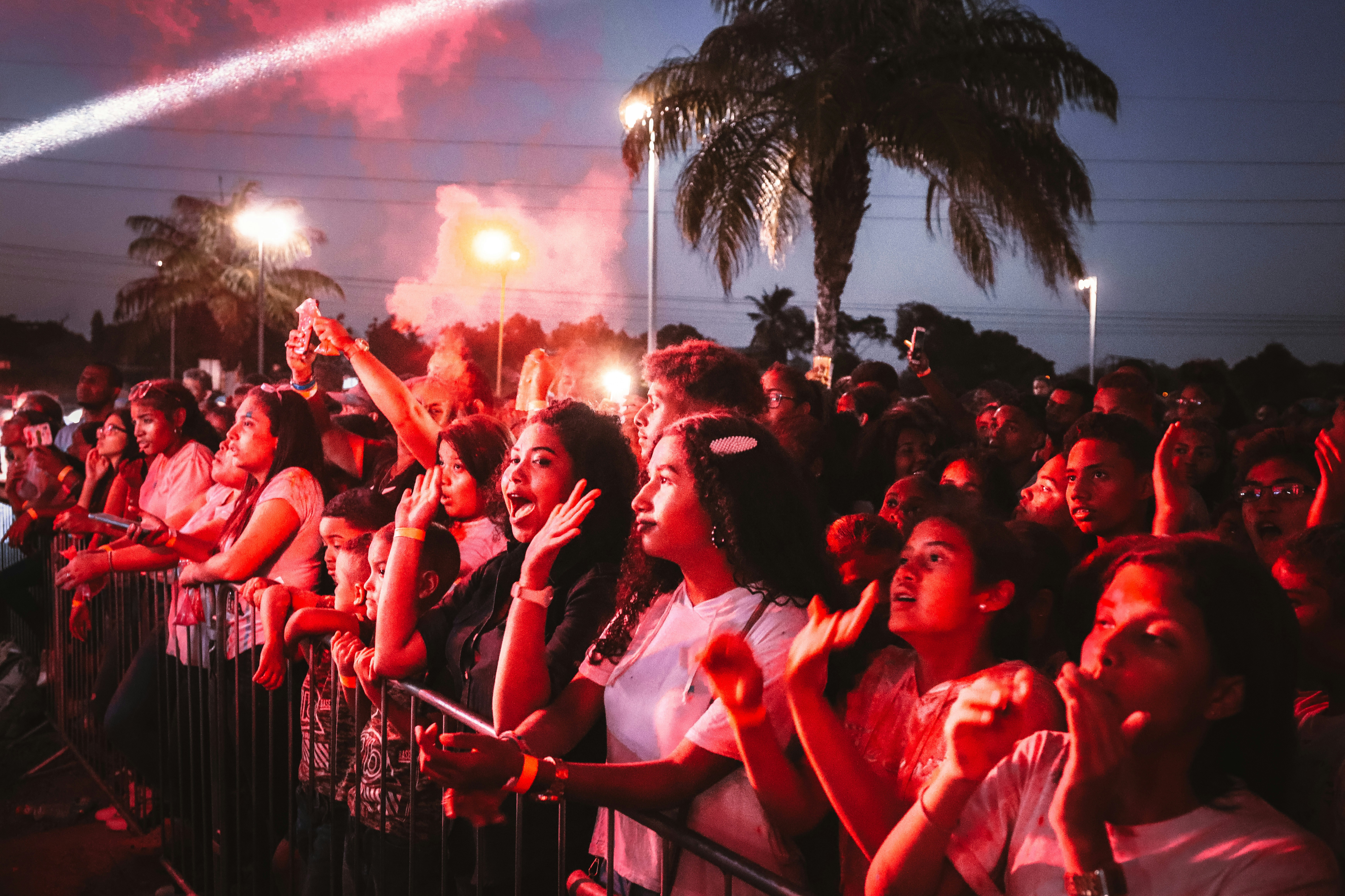 people in red shirts sitting on black metal fence during night time