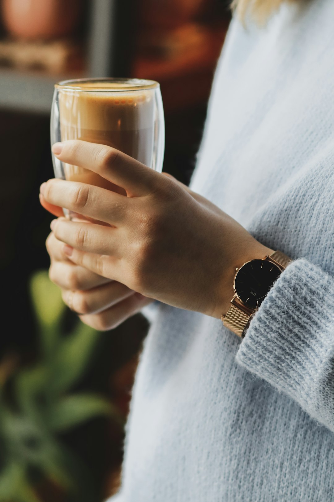 person in gray sweater holding clear drinking glass