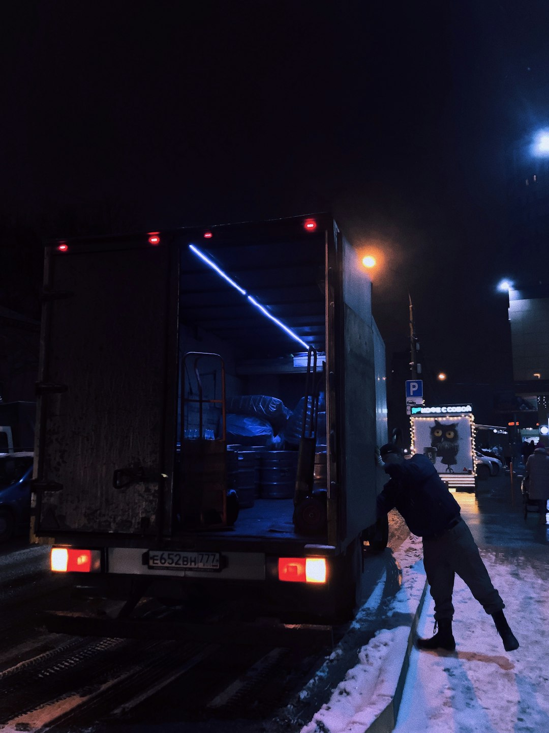 man in black jacket and blue denim jeans standing near truck during night time