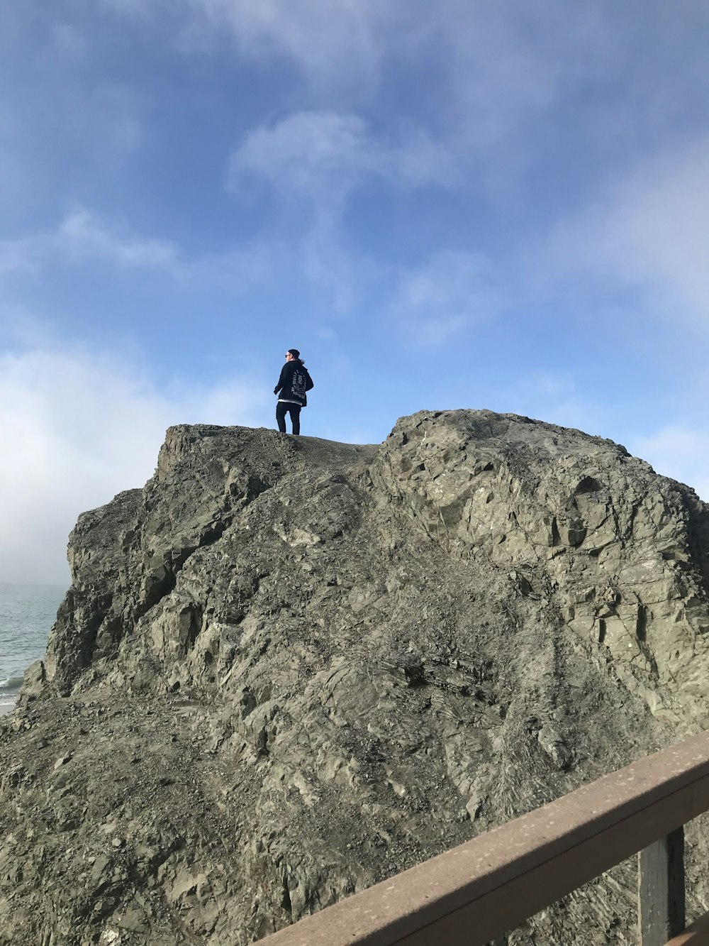 person in black jacket and black pants standing on gray rock formation during daytime