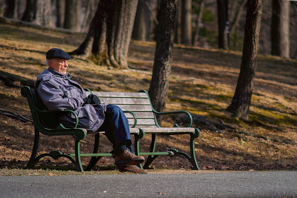 man in black jacket sitting on brown wooden bench